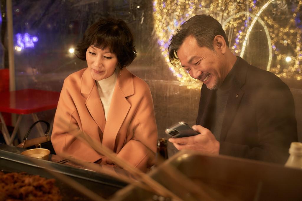 映画『ハッピーニューイヤー』のシーン、街頭の屋台で座っている中年のカップル