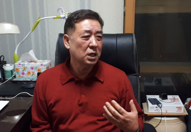 尹泰植现代日常环境中的场景，一个中年男子用手势表达自己的某种观点或故事。