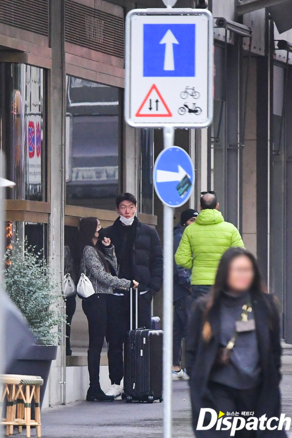 孝敏与黄义助站在酒店外，周围有其他游客持伞走过。Dispatch的照片显示了这对情侣的亲密无间和他们旅途中的日常瞬间。