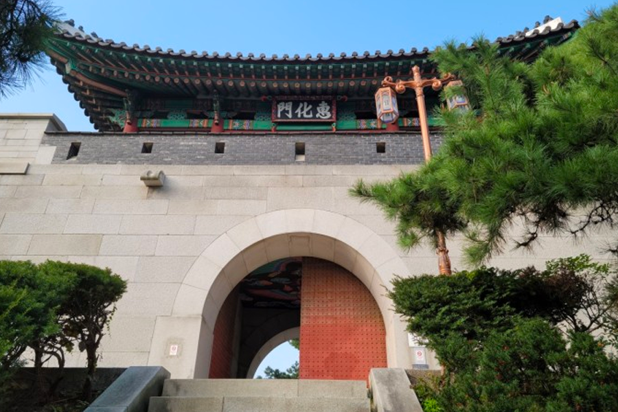서울의 전통 성문인 혜화문의 전경. 두꺼운 돌벽과 전통 기와가 어우러져 아름다운 풍경을 만들어내고 있습니다.