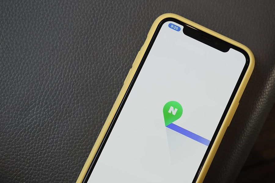 一部智能手機屏幕上顯示Naver地圖圖標，手機置於暗色背景中，打造出現代和高科技的氛圍。