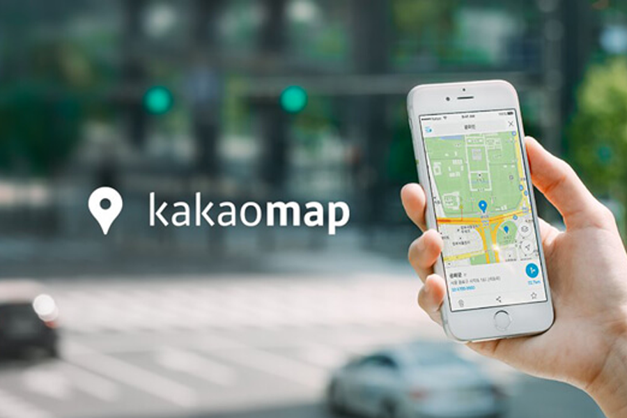 用戶正查看KakaoMap應用程式，手機畫面顯示一段導航路線，背景是明亮模糊的街景。