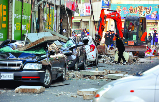 韓國浦項地震的損壞情況，兩輛汽車被倒塌的建築物砸中，街道上到處是瓦礫和旋轉的電線。