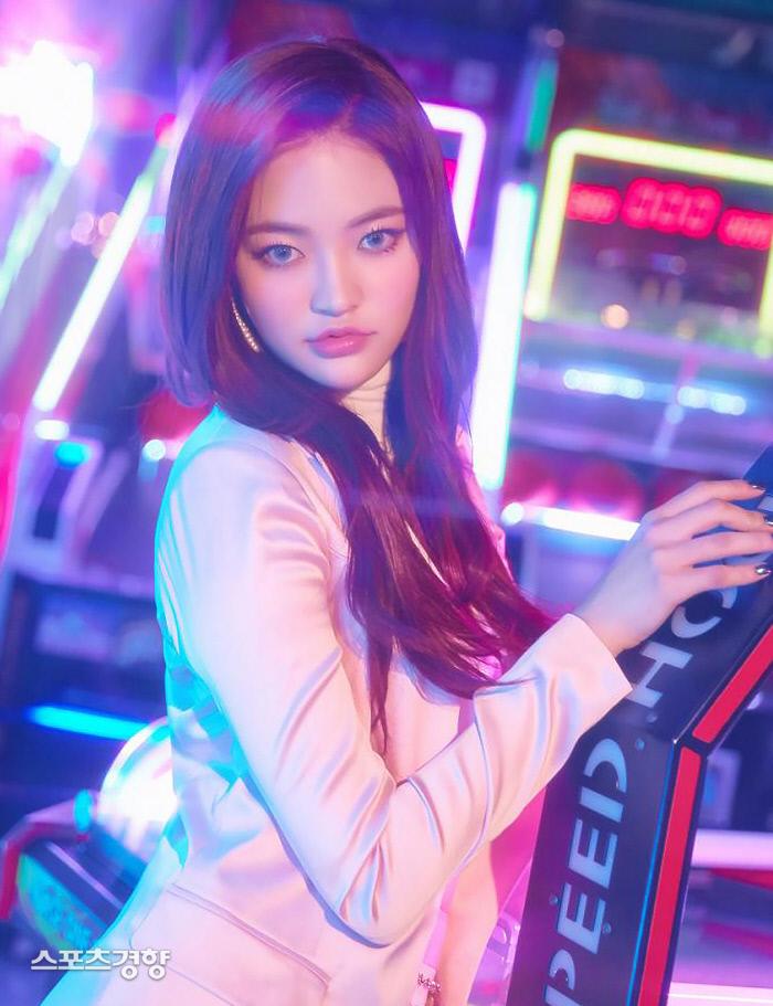 DIAの元メンバー ソミが光沢のあるジャケットを着てアーケードゲームの前に立っている場面。