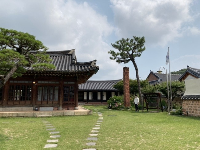 綠色草坪旁的韓國傳統韓屋，代表著傳統文化中的平衡和美學設計。 - 韓國文化遺產