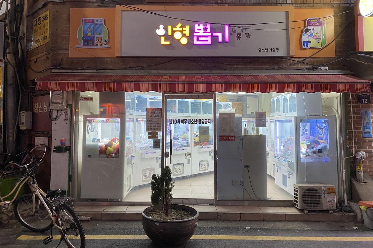 Illuminated sign of a claw machine store in Seoul, inviting visitors for entertainment and prize-winning