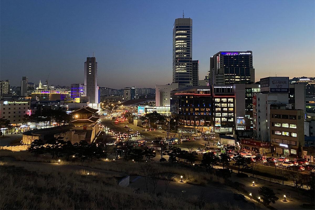 Panoramic city view from Heunginjimun Park showing Seoul's skyline and bustling streets at dusk