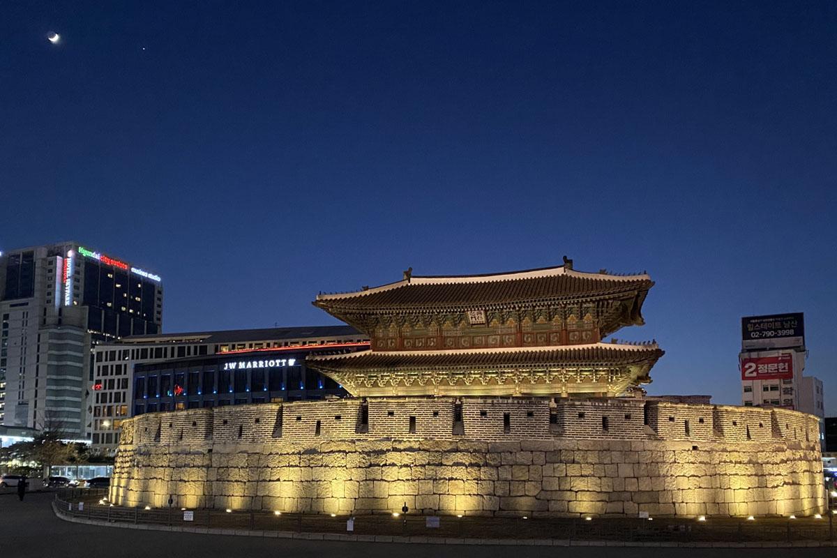 Night view of Heunginjimun Gate in Seoul, illuminated by lights with surrounding modern buildings