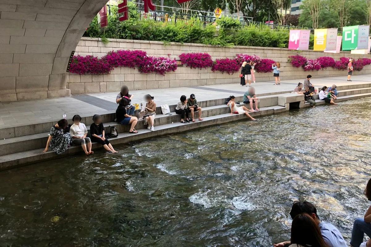 Pedestrians enjoying a leisurely evening along the steps of Cheonggyecheon Stream in Seoul