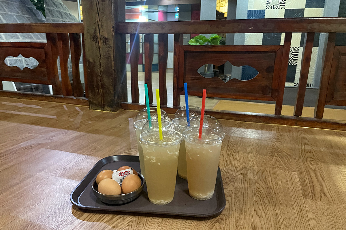 Ly nước gạo truyền thống và trứng luộc được bày trên bảng gỗ, một phần không thể thiếu trong liệu trình thưởng thức tại jjimjilbang Hàn Quốc