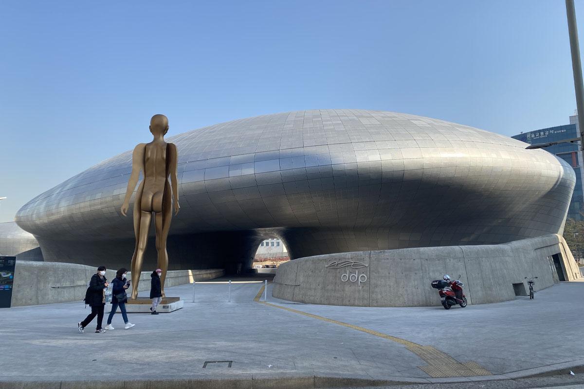 Exterior view of the Dongdaemun Design Plaza in Seoul, featuring its futuristic architecture and outdoor sculpture