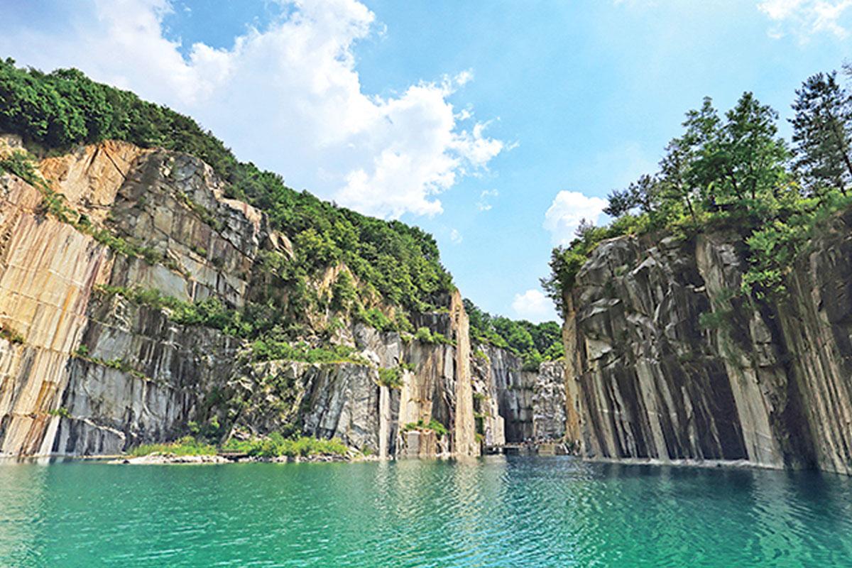 หน้าผาหินทรงสูงที่ตั้งอยู่รอบๆ น้ำสีเขียวใสดูสงบ ราวกับเป็นธรรมชาติที่หลบซ่อนอยู่ในเมืองโพชอน จังหวัดคยองกีโด ประเทศเกาหลีใต้.