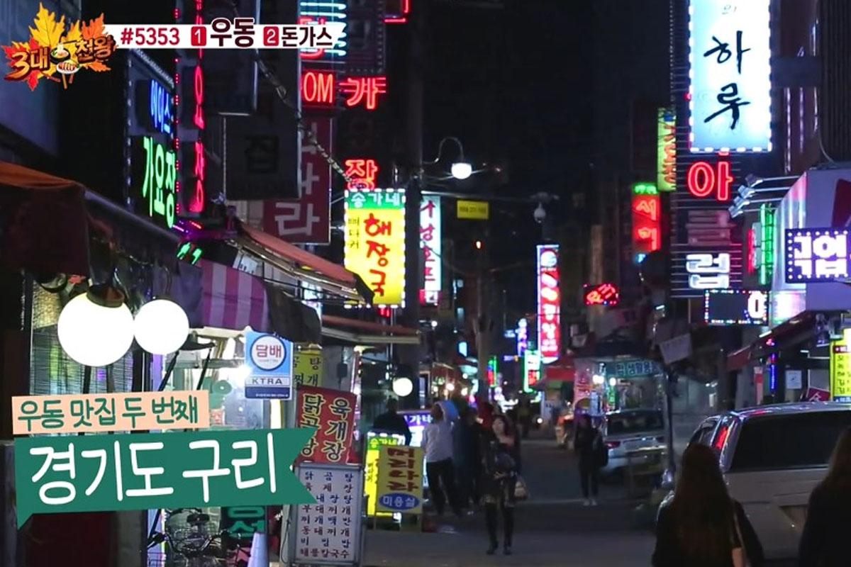 ย่านถนนสายกลางคืนที่เต็มไปด้วยป้ายไฟนีออนหลากสีและผู้คนเดินทาง บ่งบอกถึงความคึกคักในเมืองคูรี จังหวัดคยองกีโด ประเทศเกาหลีใต้.