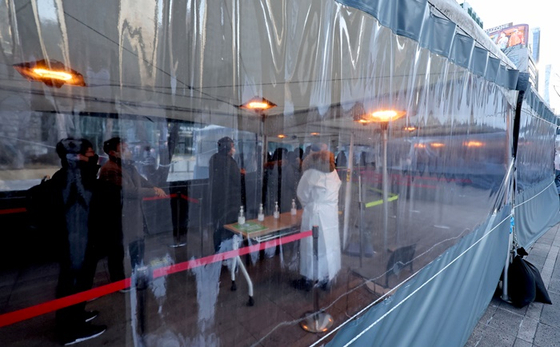 韩国户外COVID-19检测站的透明隔离棚，等待检测的市民按秩序排队进行检测。