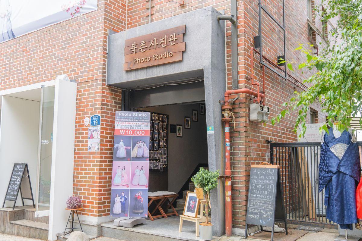 ด้านนอกของ Bukchon Photo Studio ที่มีป้ายถ่ายภาพฮันบก