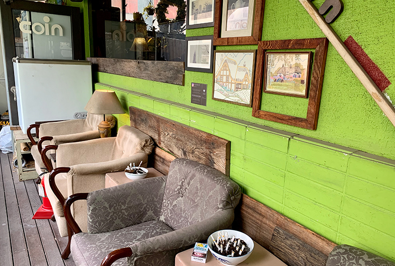 Cafe Coin Myeongdong салбарын терраст байрлуулсан тав тухтай суудал ба уран сайхны зурагтай хана.