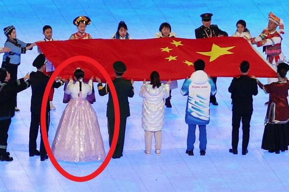 北京冬季オリンピック開会式で、韓服を身に着けた女性が中国の国旗を掲げる場面