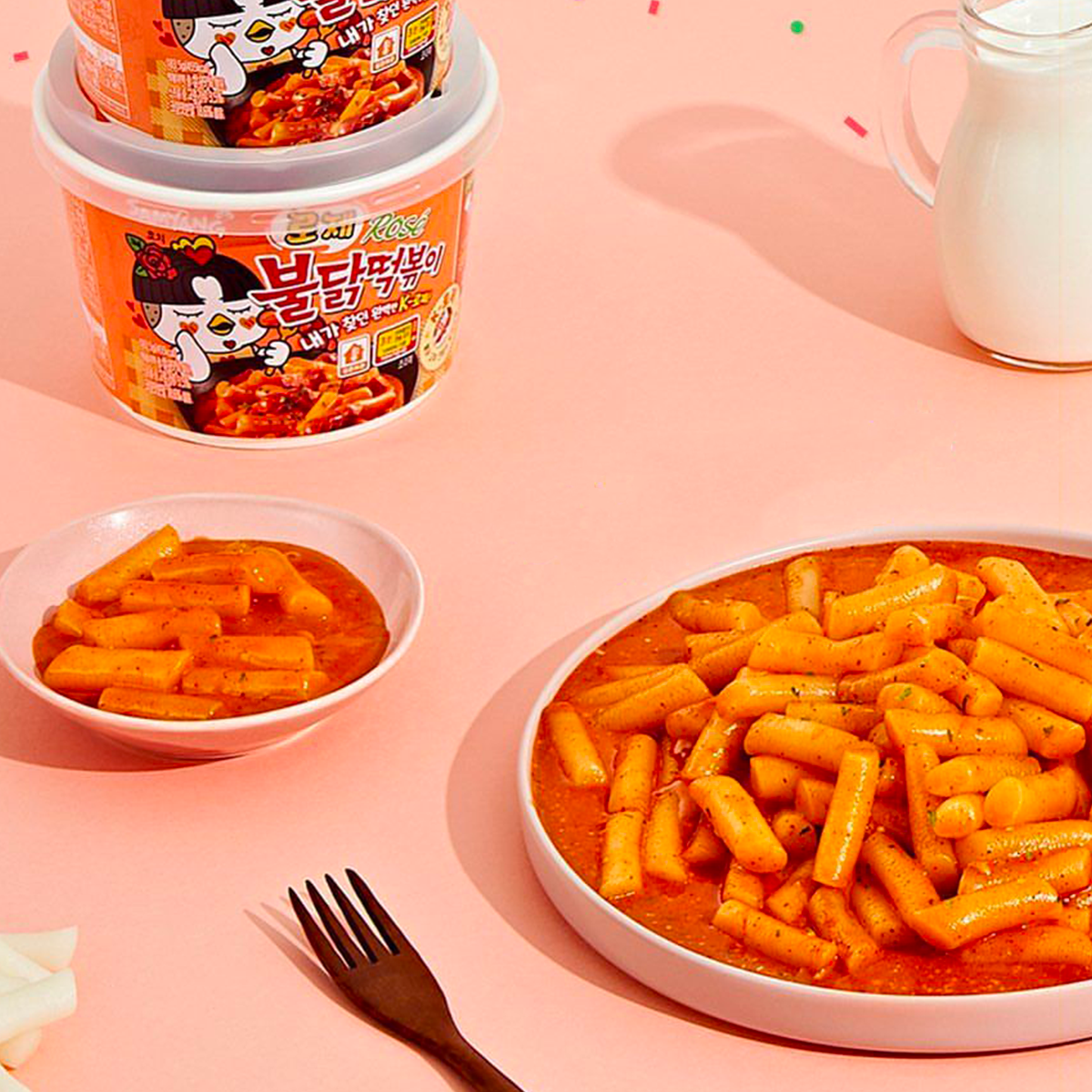 Упаковка розовых Samyang Buldak Tteokbokki с разговором о сладком и остром вкусе.