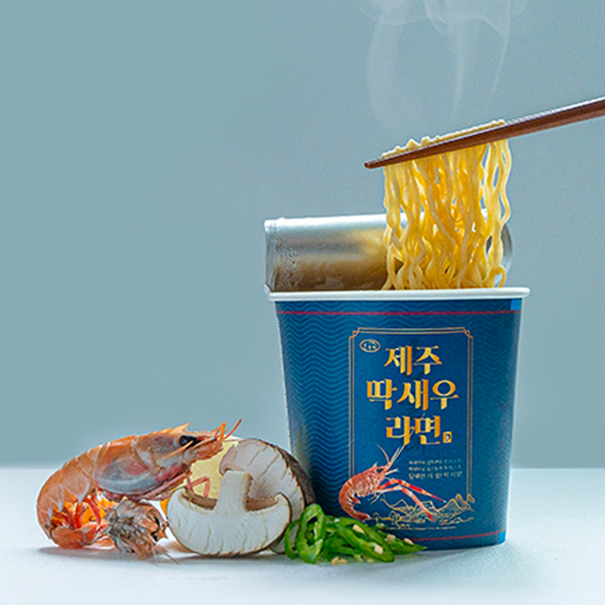 Чашка лапши Jeju Island Shrimp Ramen с изображением лапши и морепродуктов рядом.