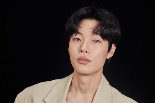 ベージュのスーツを着た韓国の俳優、リュ・ジュンヨルのおぼろげな姿と黒の背景。