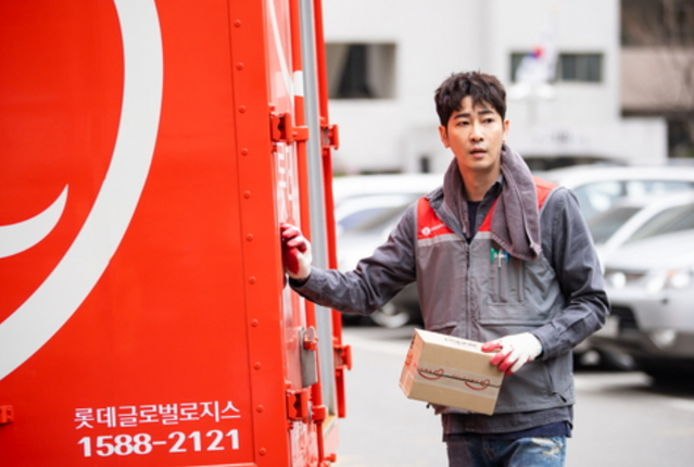 遞送員站在紅色貨車旁，手持紙箱進行快遞服務。