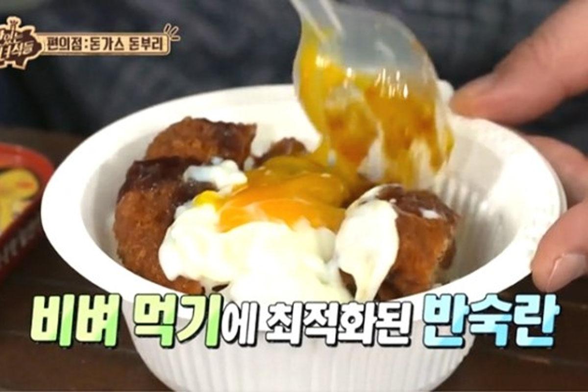 Cận cảnh món thịt heo chiên giòn donburi với lòng đỏ trứng mềm mại vừa chảy trên mặt tại cửa hàng tiện lợi.