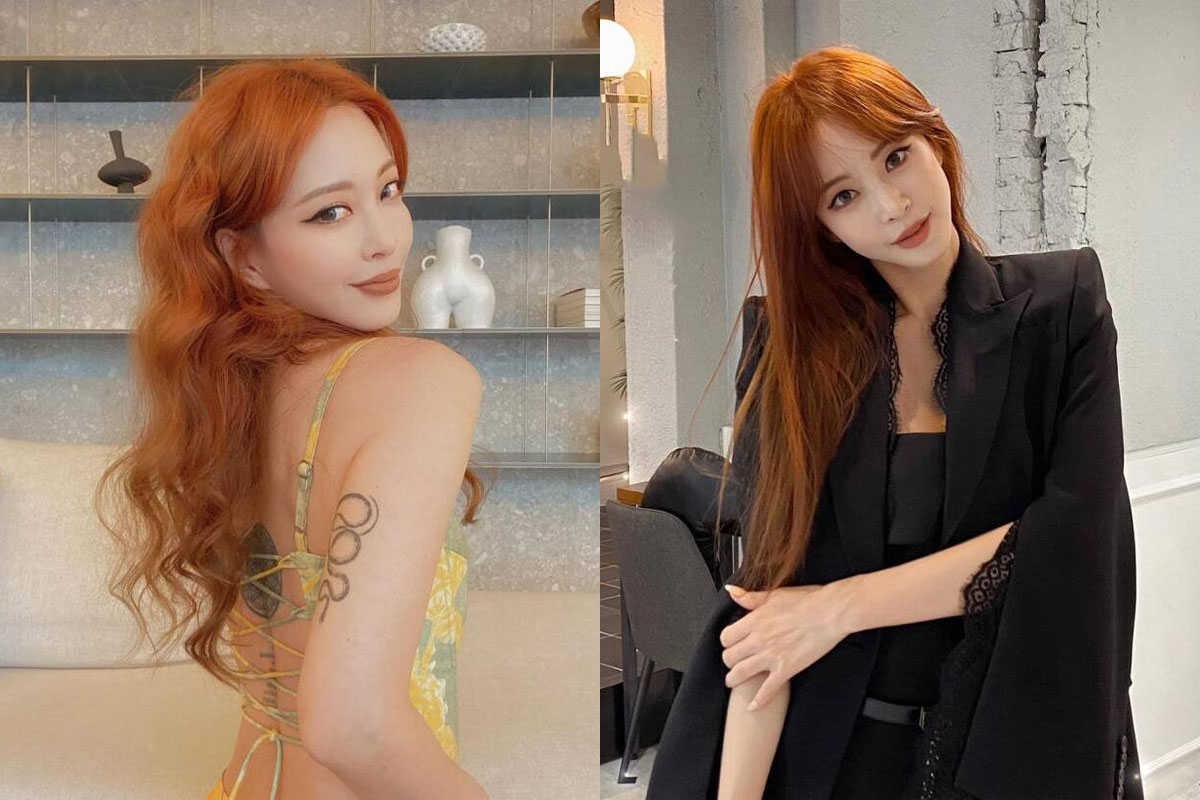 Personne avec des cheveux orange vif, portant une robe jaune dos-nu, montrant un tatouage sur le bras.