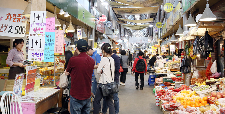 Mercato affollato in Seoul con varie bancarelle alimentari e decorazioni vivaci.