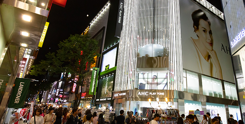 Strade animate di Myeongdong di notte a Seoul, piene di negozi e insegne luminose.