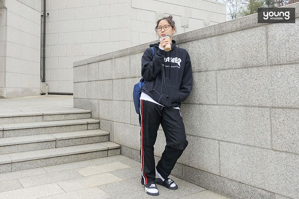 学生穿着休闲运动装，站在建筑物旁边，显现出考试期间特有的匆忙状态。