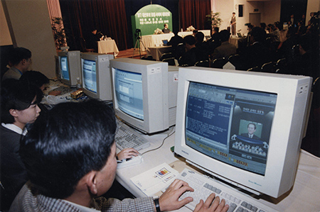 1980年代韩国的PC通信网络文化介绍，展现了一名技术人员在使用显示器的场景。