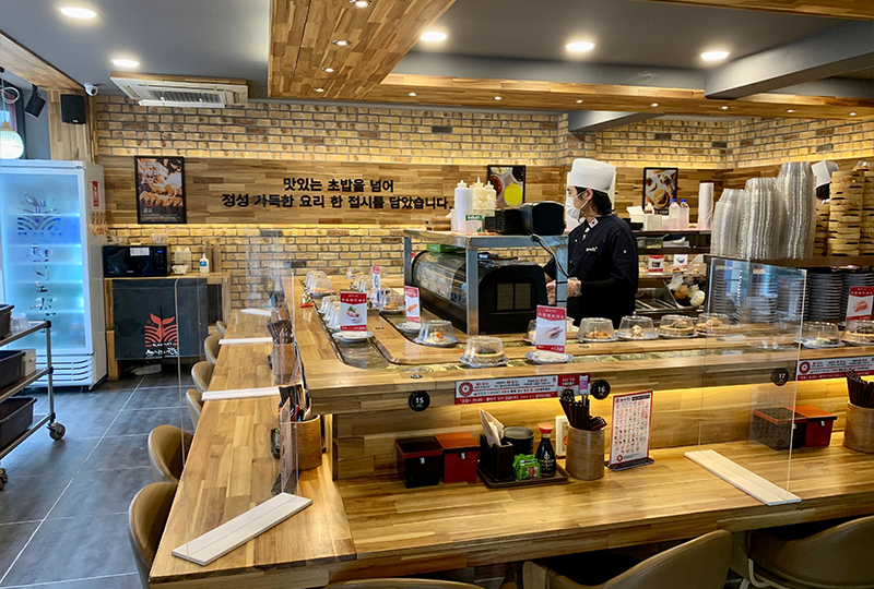 Sushi Nokando壽司店的內部吧檯座位，展示各種壽司盤在轉動的場景。