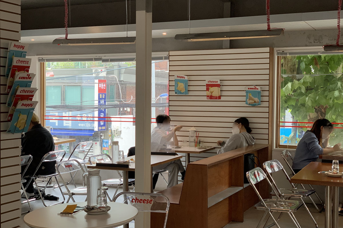 Sillas y mesas en el interior de Happy Cheese Smile, resaltando la decoración moderna y minimalista.