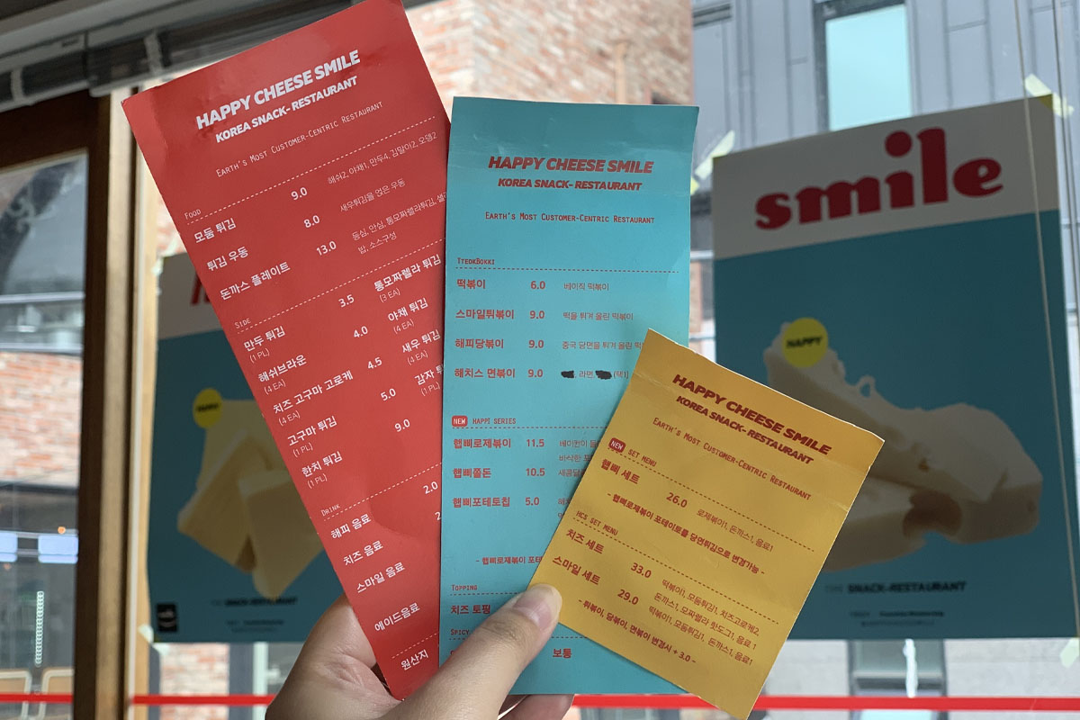 Mesa con un plato servido con chuleta de cerdo, tteokbokki, y varias salsas listas para comer en Happy Cheese Smile.