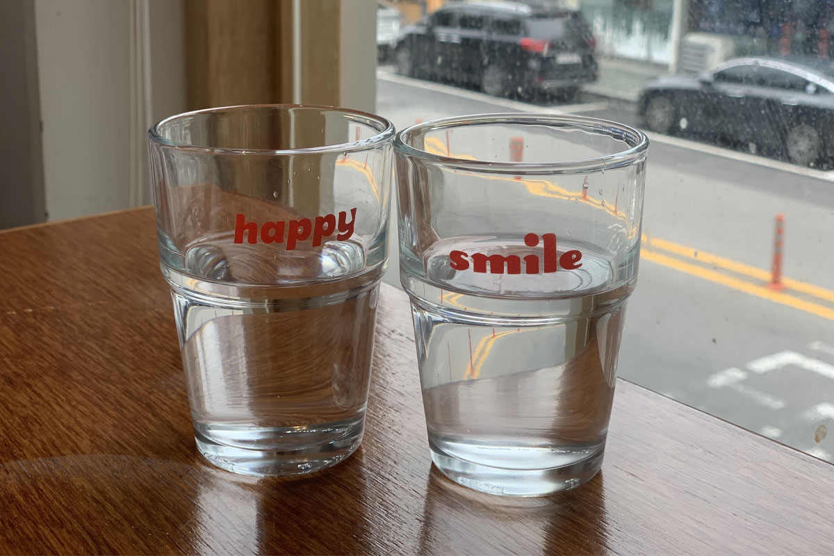 Menús en colores vivos de Happy Cheese Smile en mano, con un póster en el fondo que detalla los alimentos y platos ofrecidos.