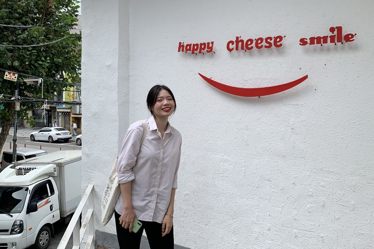 Cartel de Happy Cheese Smile en la entrada del restaurante en letras rojas sobre una pared blanca.