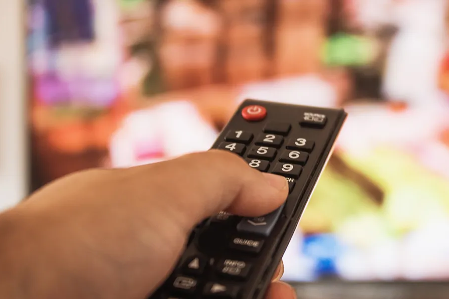 手持遙控器面對電視屏幕，象徵著韓國演藝圈和國家政策對音樂節目中衣著和動作的審查。