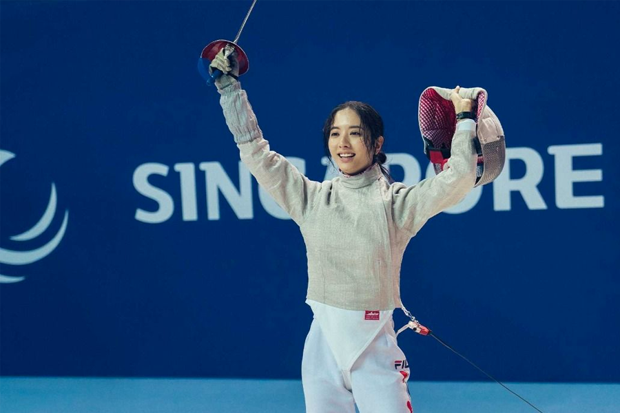 韩国击剑运动员正在比赛中，背景是新加坡的标志