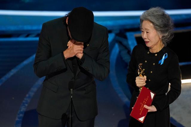 ユン・ヨジョンが第94回アカデミー賞授賞式でオスカートロフィーを持ち、ウクライナ侵攻に対する支持の象徴として青いリボンを付けています。