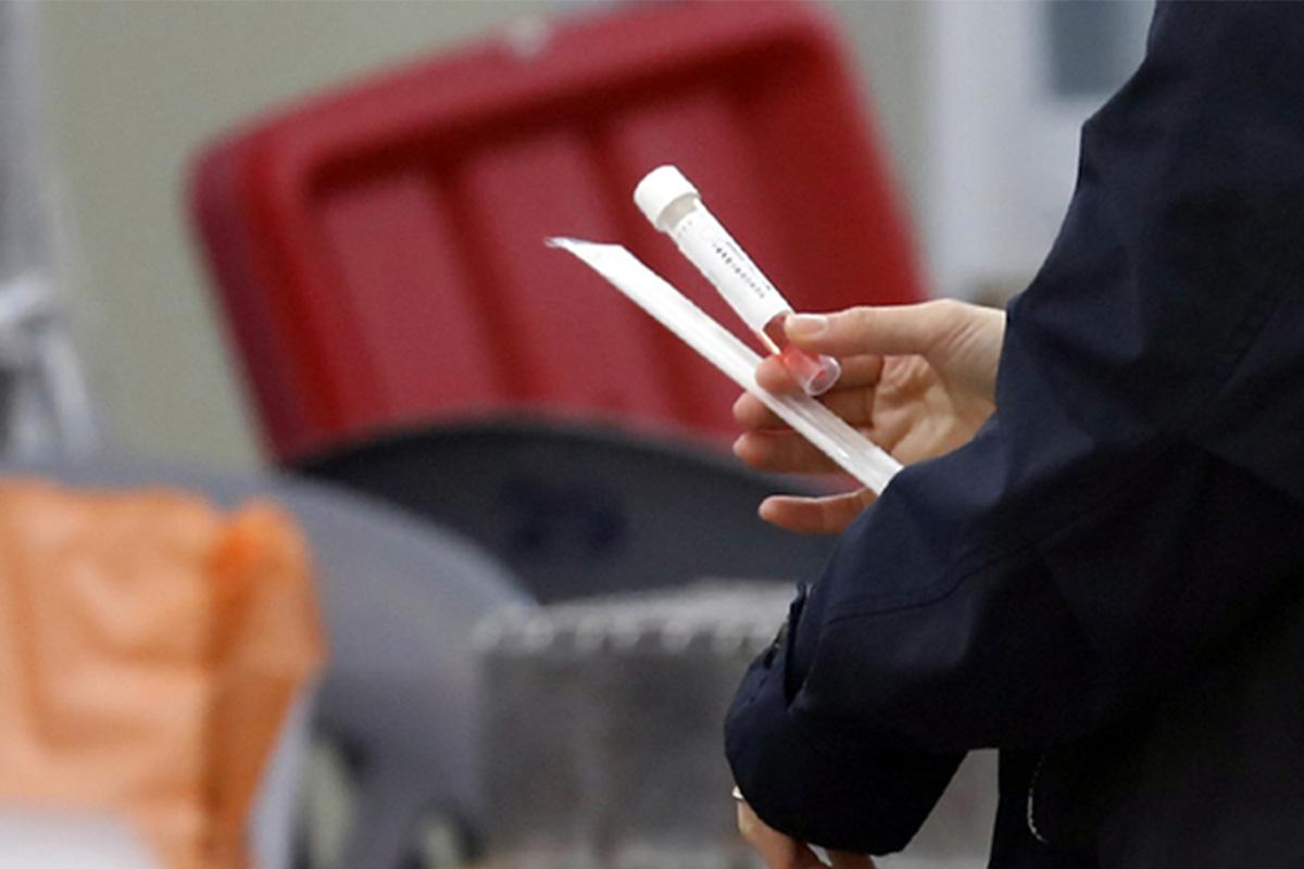 บุคคลถือหลอดทดลองในมือในสถานการณ์ที่เกี่ยวข้องกับโควิด-19 ในเกาหลีใต้