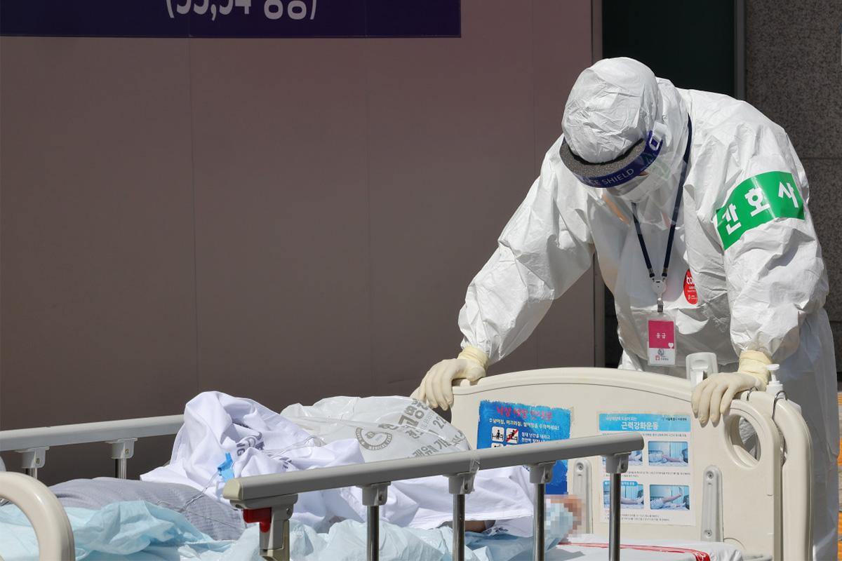เจ้าหน้าที่ทางการแพทย์ในชุดป้องกันกำลังจัดการกับเตียงคนไข้ COVID-19 ในเกาหลีใต้