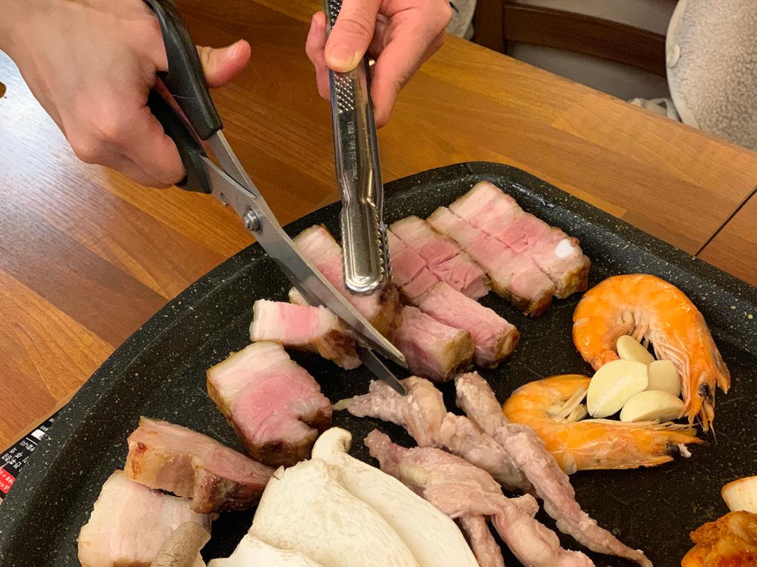 店员使用剪刀和钳子切割烤好的猪肉,奉卓瓦瓮BBQ呈现专业服务