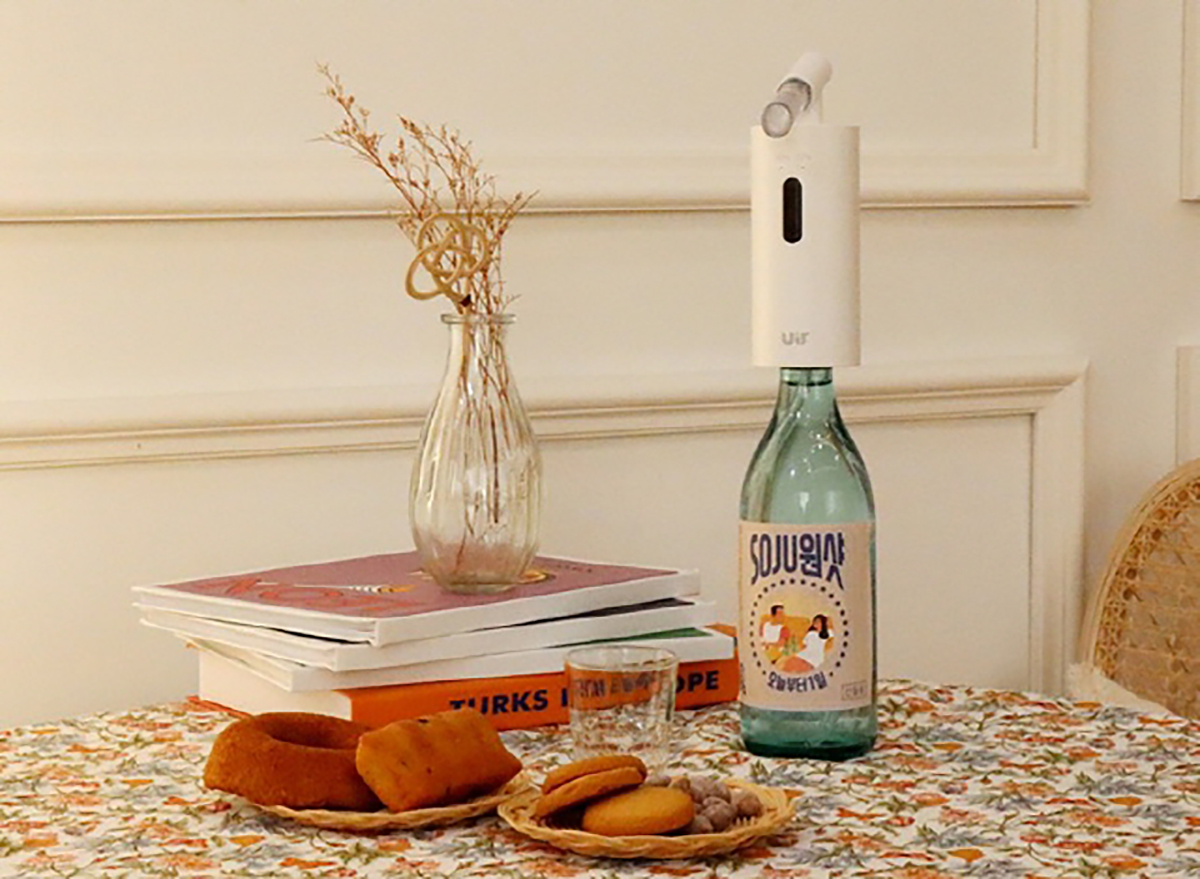 白色的自动倒酒器与包装盒一起展示，放置在装饰桌上，适合个人使用的便利设备。