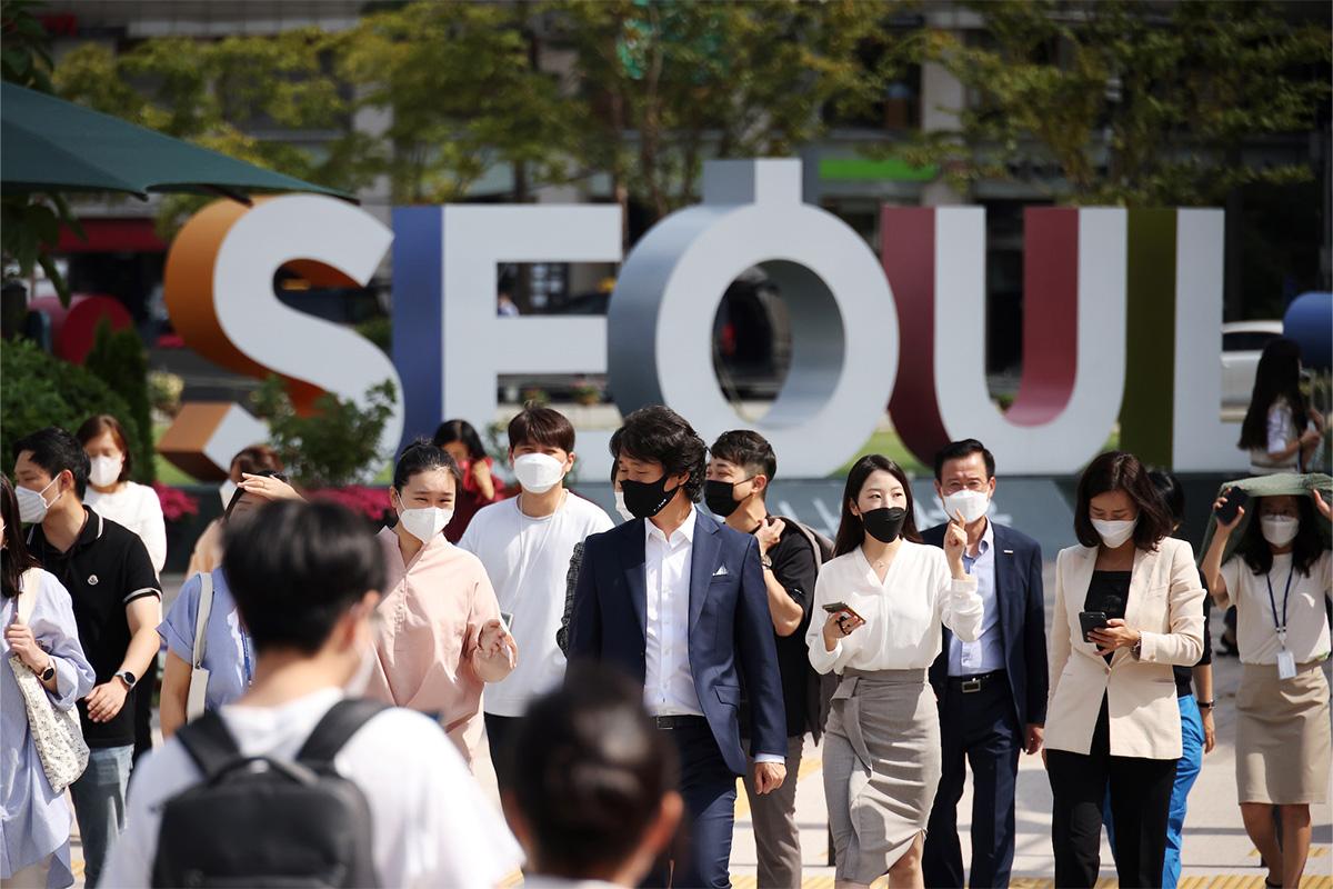 กลุ่มคนเดินผ่านป้ายสีสันตามคำว่า SEOUL แสดงให้เห็นถึงชีวิตปกติใหม่ในกรุงโซล เกาหลีใต้ หลังการผ่อนคลายมาตรการควบคุม COVID-19
