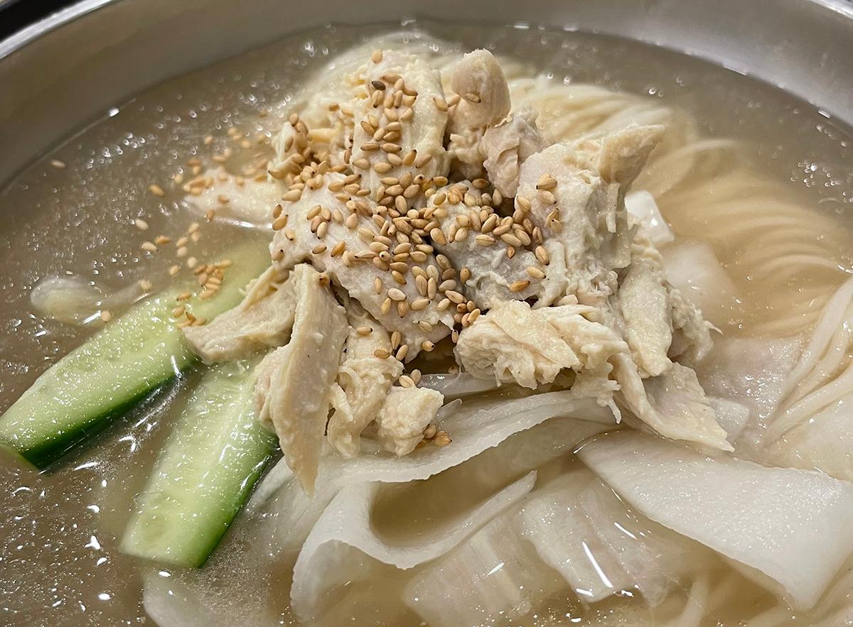 碗内渼沙里醋鸡汤面的近距拍摄，展示了细长面条和丰富汤底。