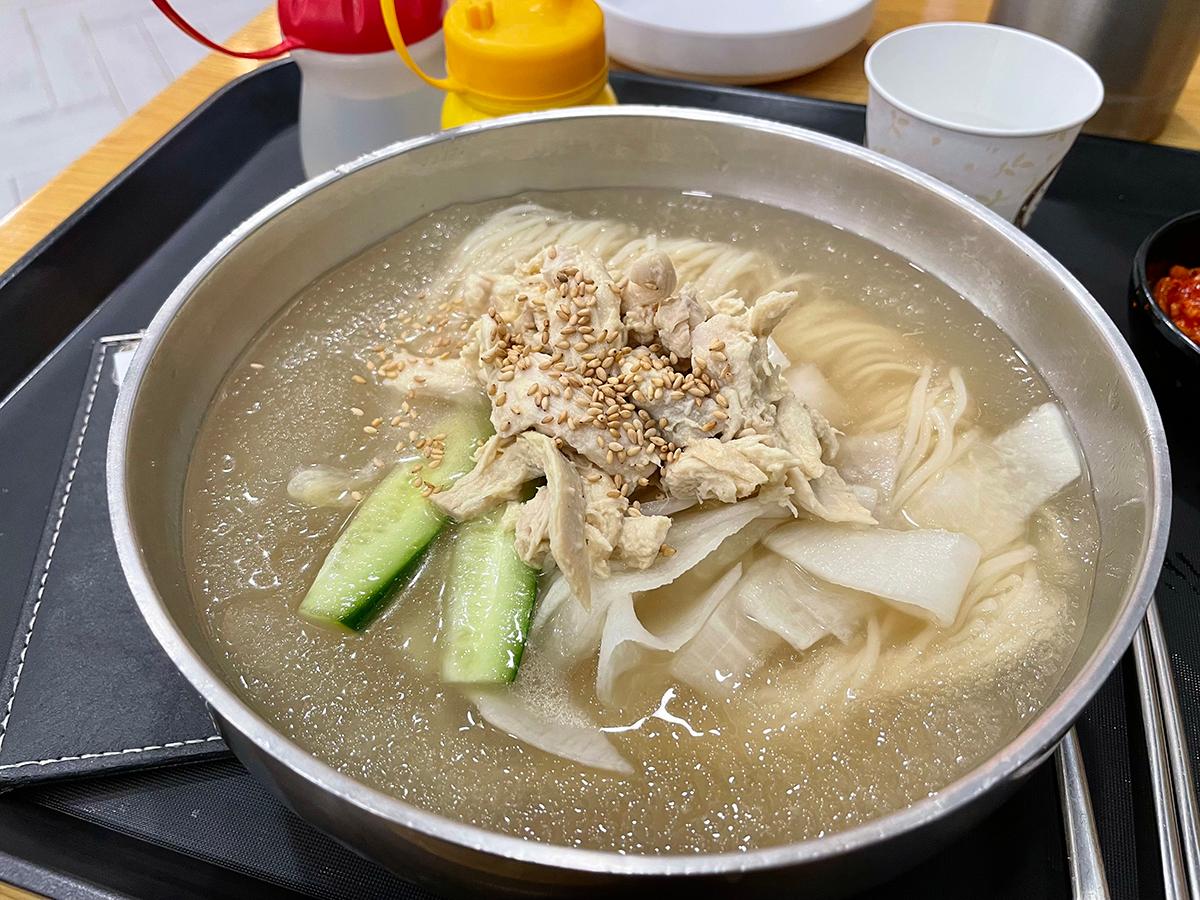 渼沙里醋鸡汤面碗内的细节，呈现爽口的冷面和新鲜鸡肉。