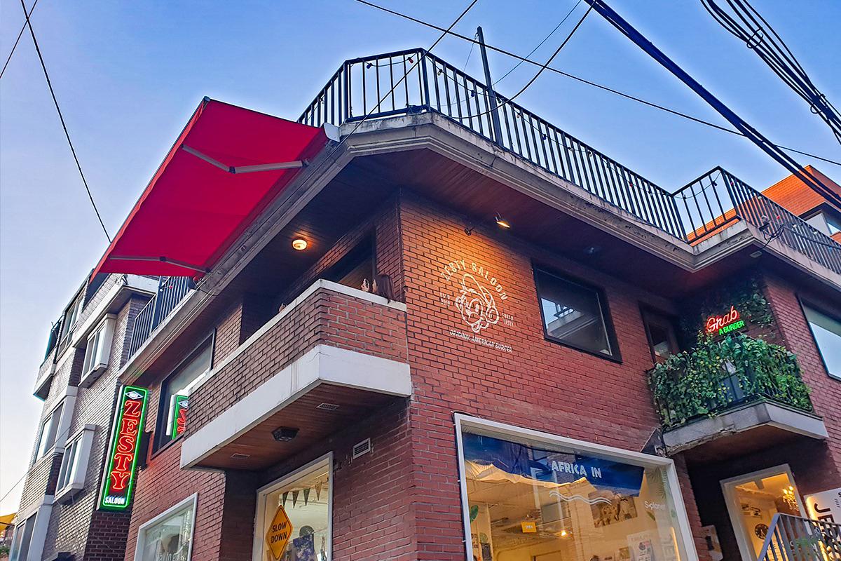 Zesty Saloon餐廳的不同角度外觀照，露天陽臺與招牌燈光搭配，讓整體風格既現代又溫馨，是享用美味漢堡的理想地點。