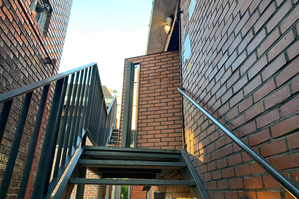 Zesty Saloon餐廳入口的樓梯，紅棕色磚牆搭配金屬欄杆，營造出美式工業風格，充滿獨特個性。