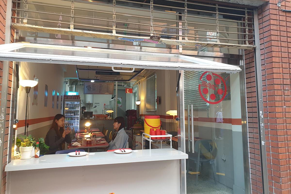 可看到店內餐桌和椅子的HDD披薩店外景，由外向內看的視角