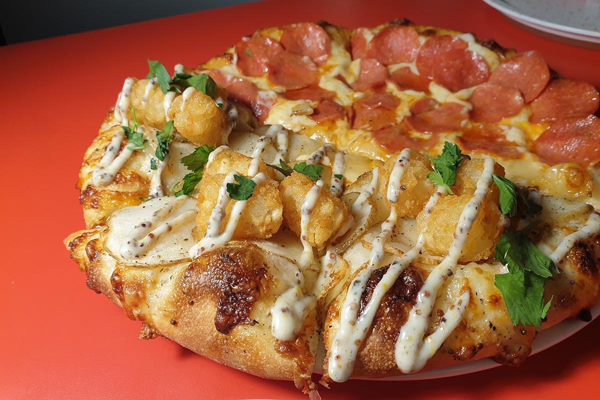 Primo piano di pizza al tartufo e al pepperoni, mostrando condimenti freschi e crosta dorata su un tavolo ben illuminato.